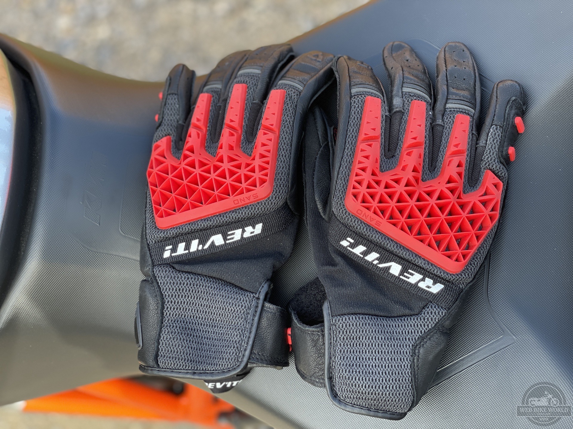 REV'IT Sand 4 Gloves in black and red lying next to each other on motorcycle seat