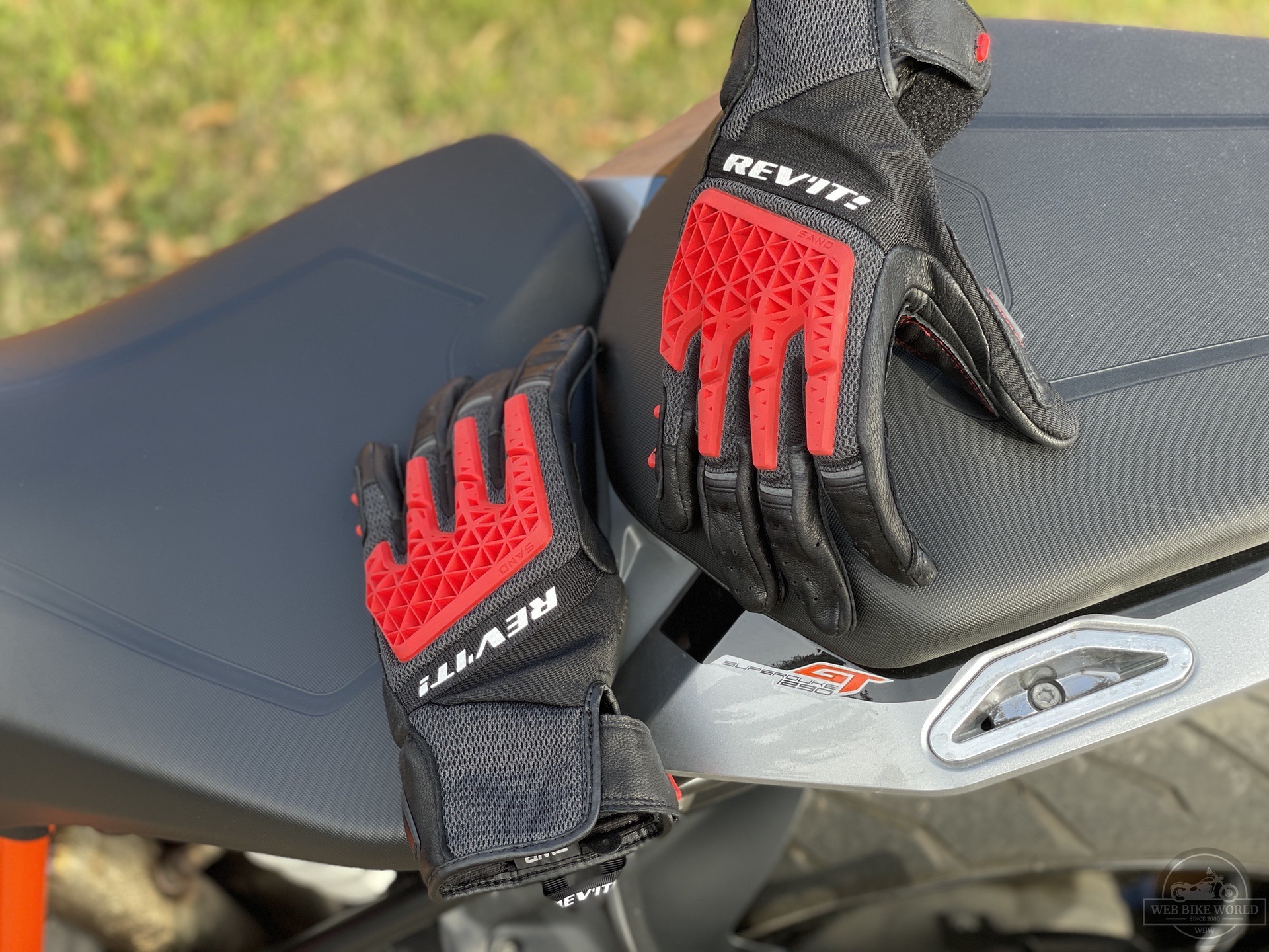 REV'IT Sand 4 Gloves in black and red lying on seat of motorcycle