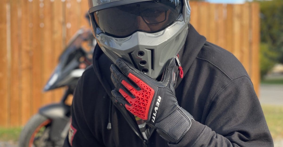Rider wearing REV'IT Sand 4 Gloves in black and red with Scorpion Covert X helmet