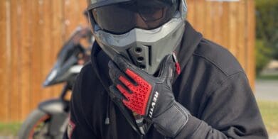 Rider wearing REV'IT Sand 4 Gloves in black and red with Scorpion Covert X helmet