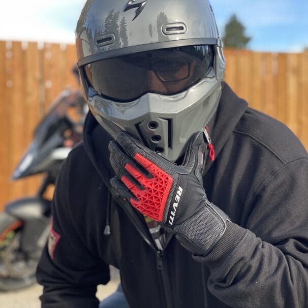 Rider wearing REV'IT Sand 4 Gloves in black and red with Scorpion Covert X helmet