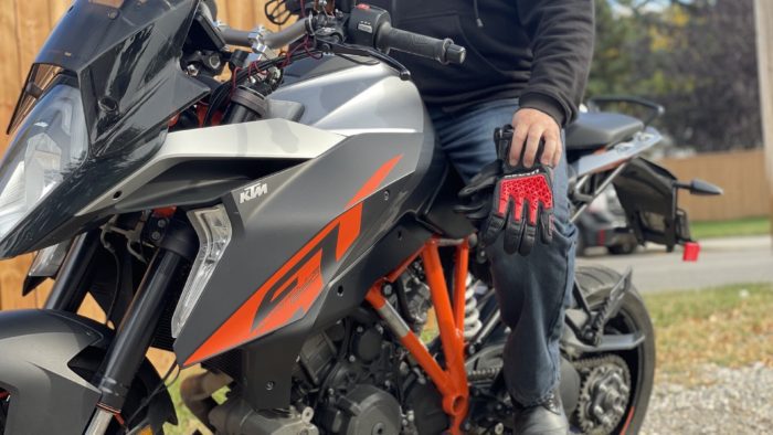 Rider holding Sand 4 Gloves while sitting on motorcycle