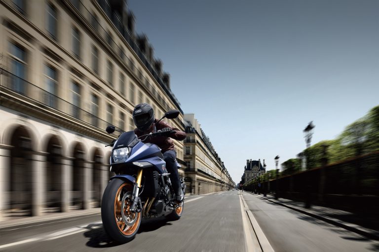 Suzuki Katana 2022: side view staged with rider and colourful background Suzuki Katana 2022: side view staged with rider and colourful background