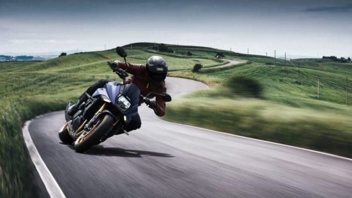 Suzuki Katana 2022: side view staged with rider and colourful background Suzuki Katana 2022: side view staged with rider and colourful background