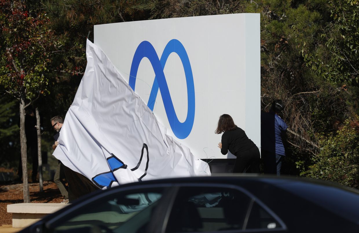 Facebook employees unveil a new logo and the name "Meta" on the sign in front of Facebook headquarters on Thursday, Oct. 28, 2021 in Menlo Park, California. A new name and logo were unveiled at Facebook headquarters after a much anticipated name change for the social media platform. (Justin Sullivan/Getty Images/TNS)