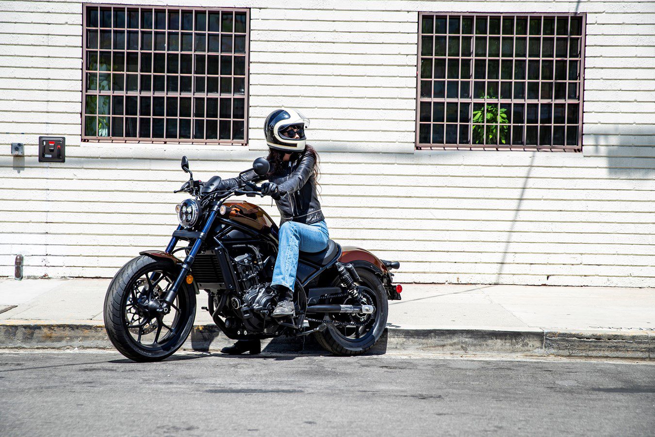 A lady riding down the street on a Honda Rebel 500