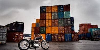 Shipping containers behind a beautiful motorcycle, symbolic of the shipping container inflation rates present in today's post