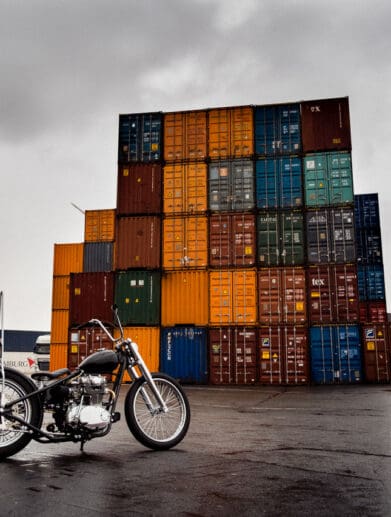 Shipping containers behind a beautiful motorcycle, symbolic of the shipping container inflation rates present in today's post