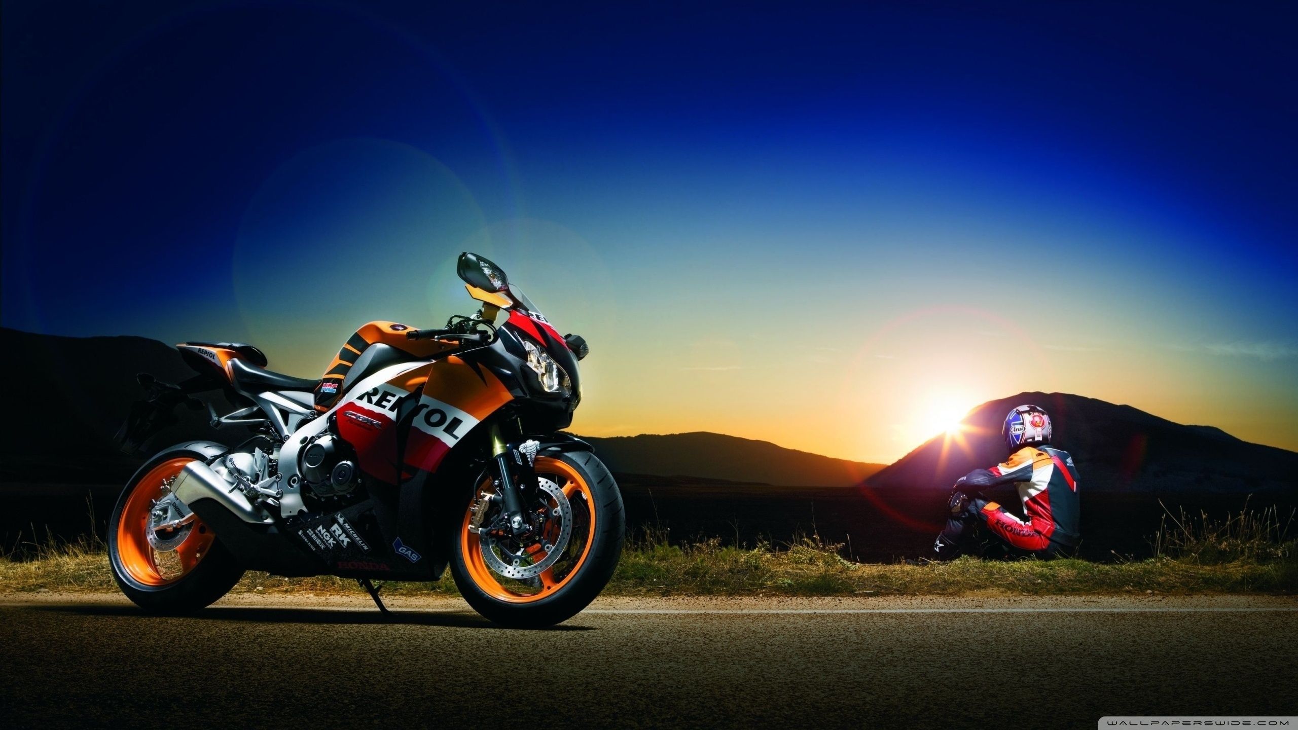 A view of a Repsol Honda replica motorcycle in front of a sunset