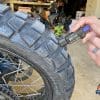 Bridgestone Battlax AdventureCross AX41 rear tire being measured in garage