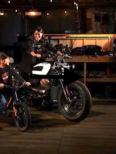 A view of a rider on the Harley-Davidson Sportster, with a child looking up to the big bike