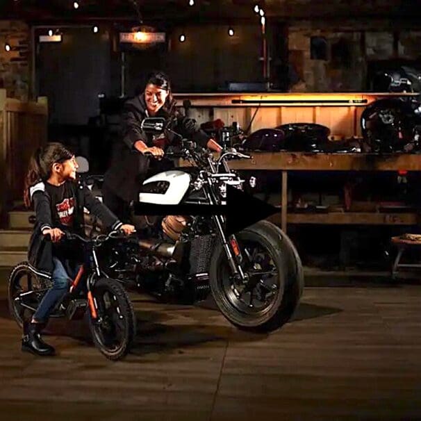 A view of a rider on the Harley-Davidson Sportster, with a child looking up to the big bike