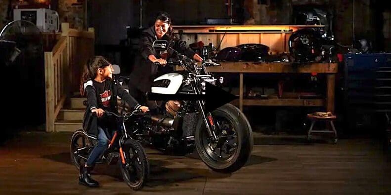 A view of a rider on the Harley-Davidson Sportster, with a child looking up to the big bike