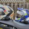 Sena SPIDER ST1 and RT1 mesh systems on two different helmets resting on motorcycle seat