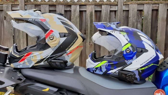 Sena SPIDER ST1 and RT1 mesh systems on two different helmets resting on motorcycle seat Sena SPIDER ST1 and RT1 mesh systems on two different helmets resting on motorcycle seat