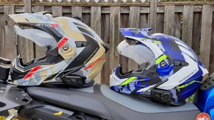 Sena SPIDER ST1 and RT1 mesh systems on two different helmets resting on motorcycle seat