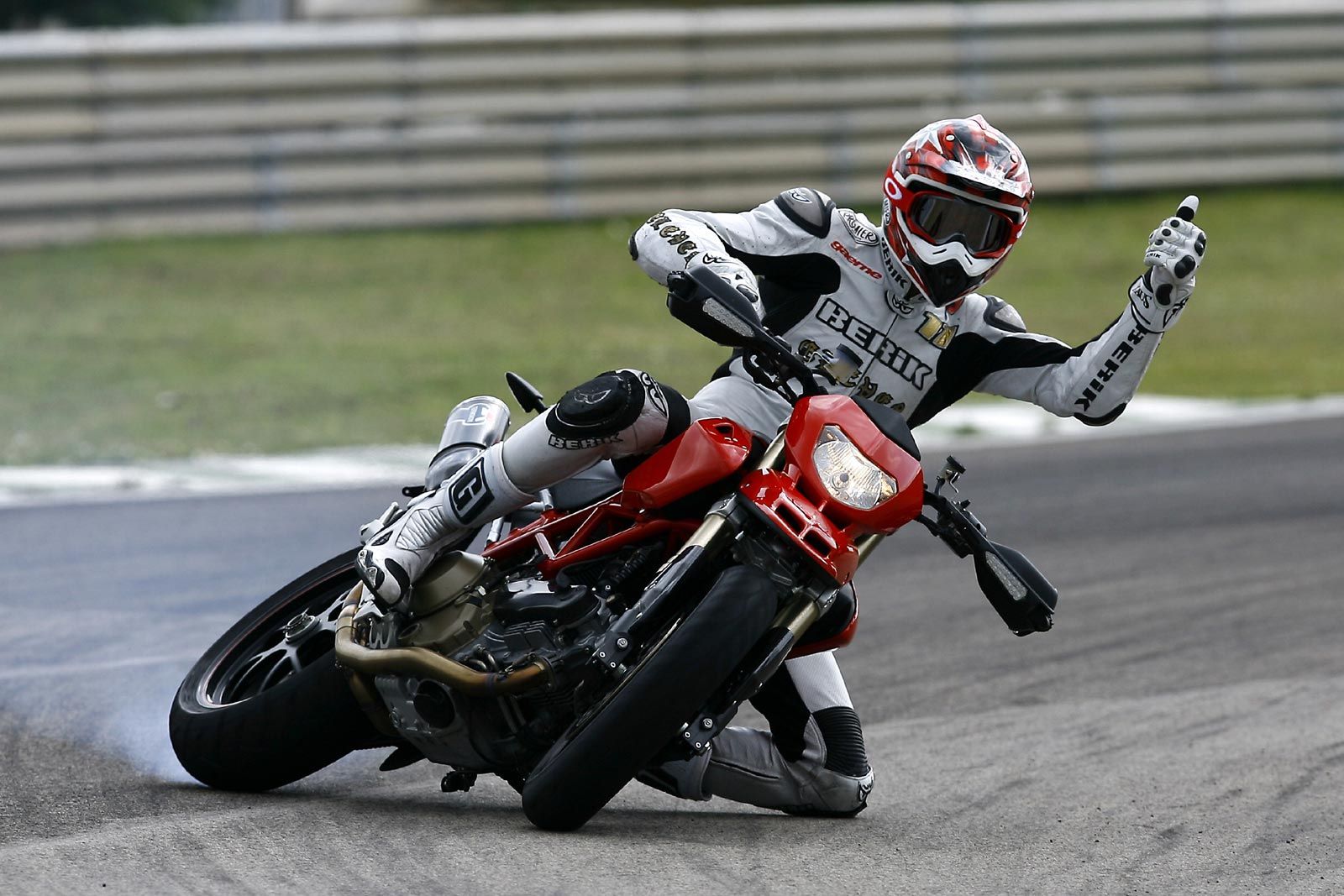 A view of a racer leaning into the twisties while giving a big thumbs up