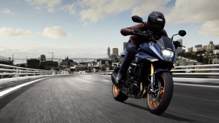 Suzuki Katana 2022: side view staged with rider and colourful background Suzuki Katana 2022: side view staged with rider and colourful background