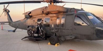 a military helicopter featuring a side-mounted electric motorcycle in prototype for stealth missions