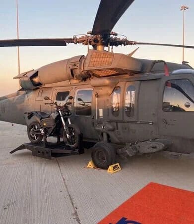 a military helicopter featuring a side-mounted electric motorcycle in prototype for stealth missions