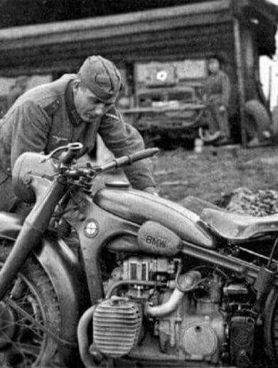 A german soldier tends to his BMW motorcycle during WWII