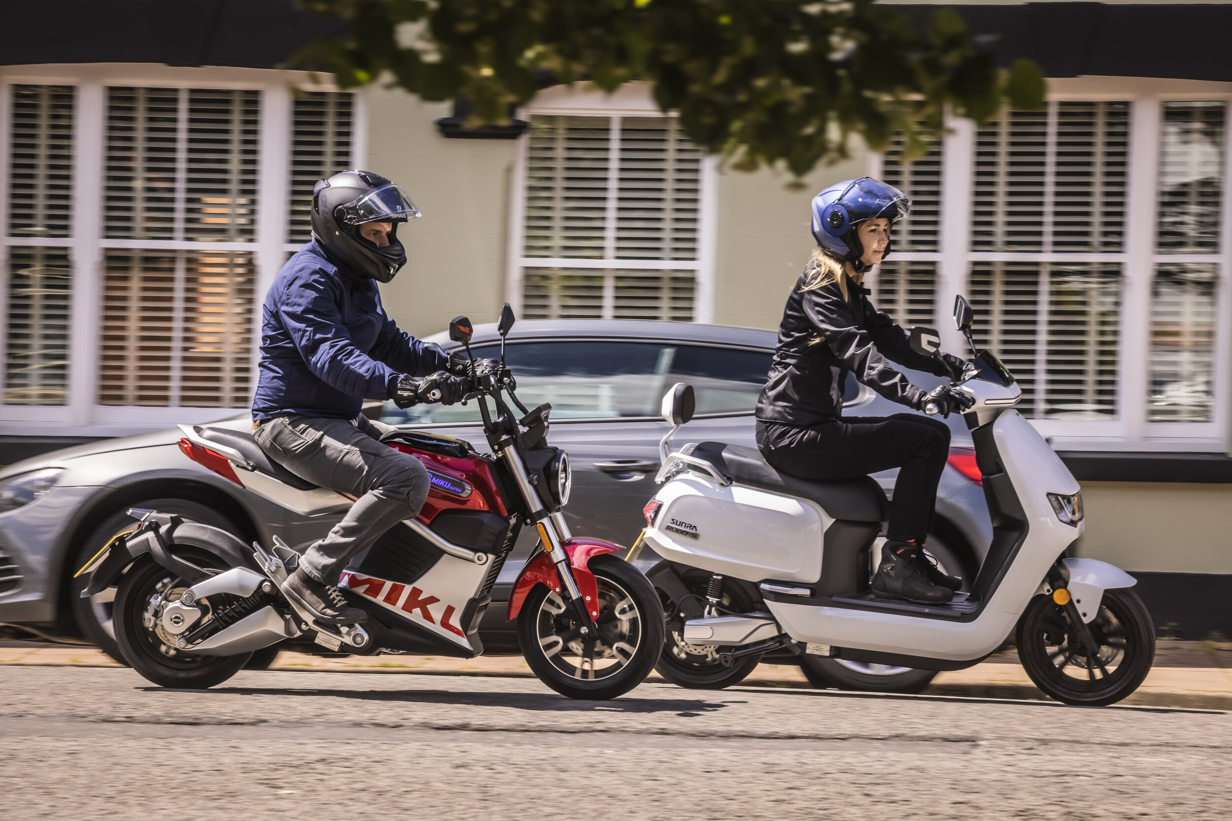 A view of Sunra motorcycles being ridden in the city / urban setting 