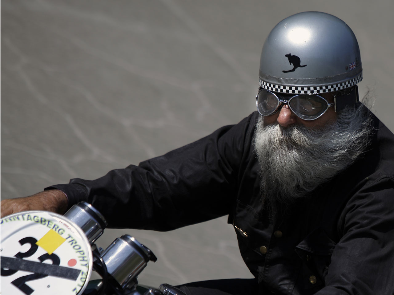 An old motorcyclist riding with helmet on a road