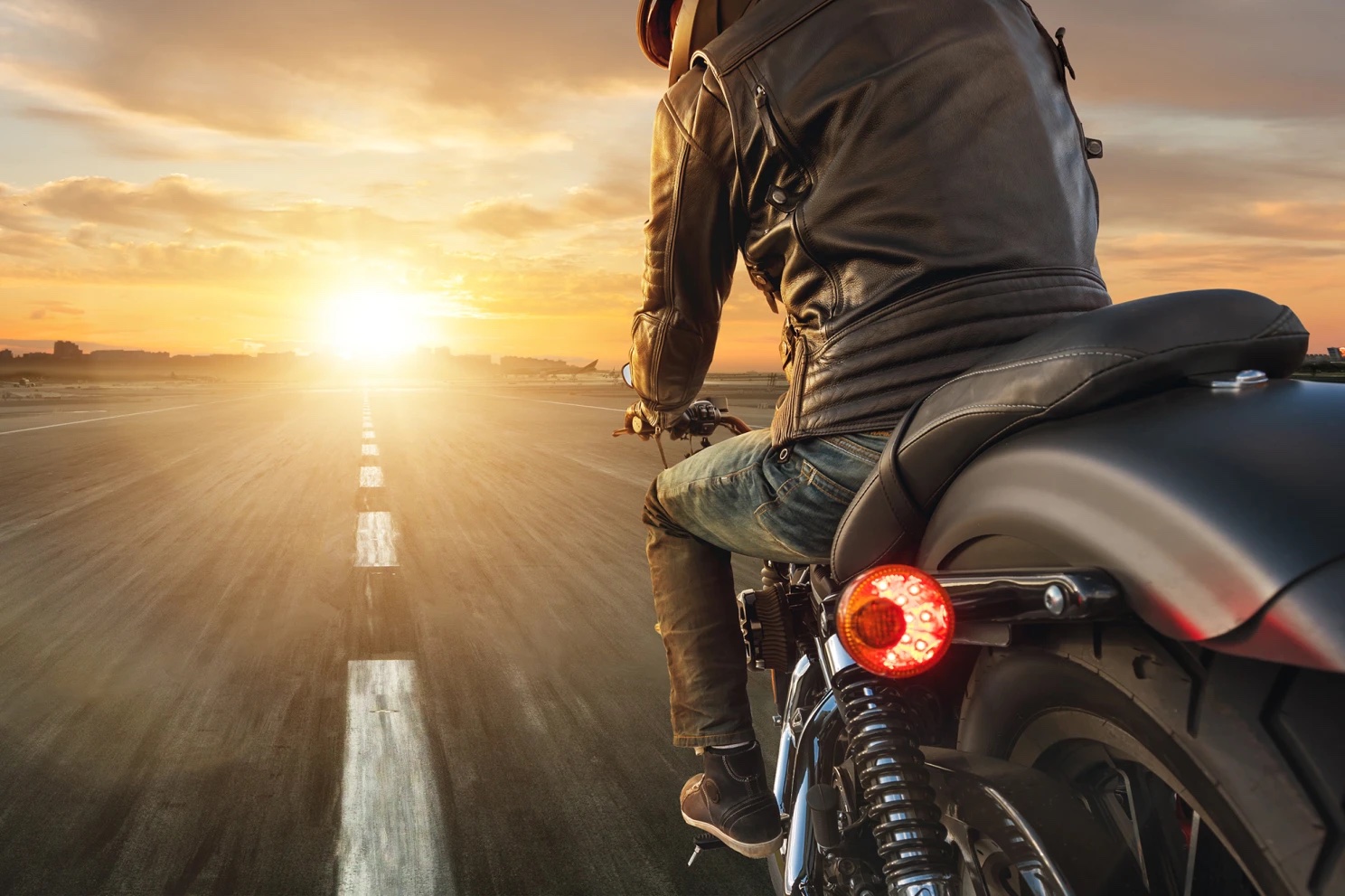 a view of a motorcyclist riding into the sunset