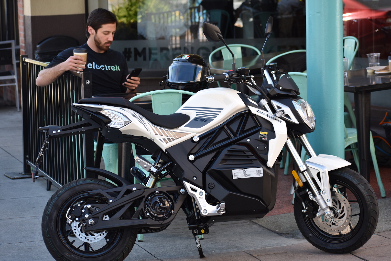 Man drinking coffee near CSC City Slicker parked on city corner