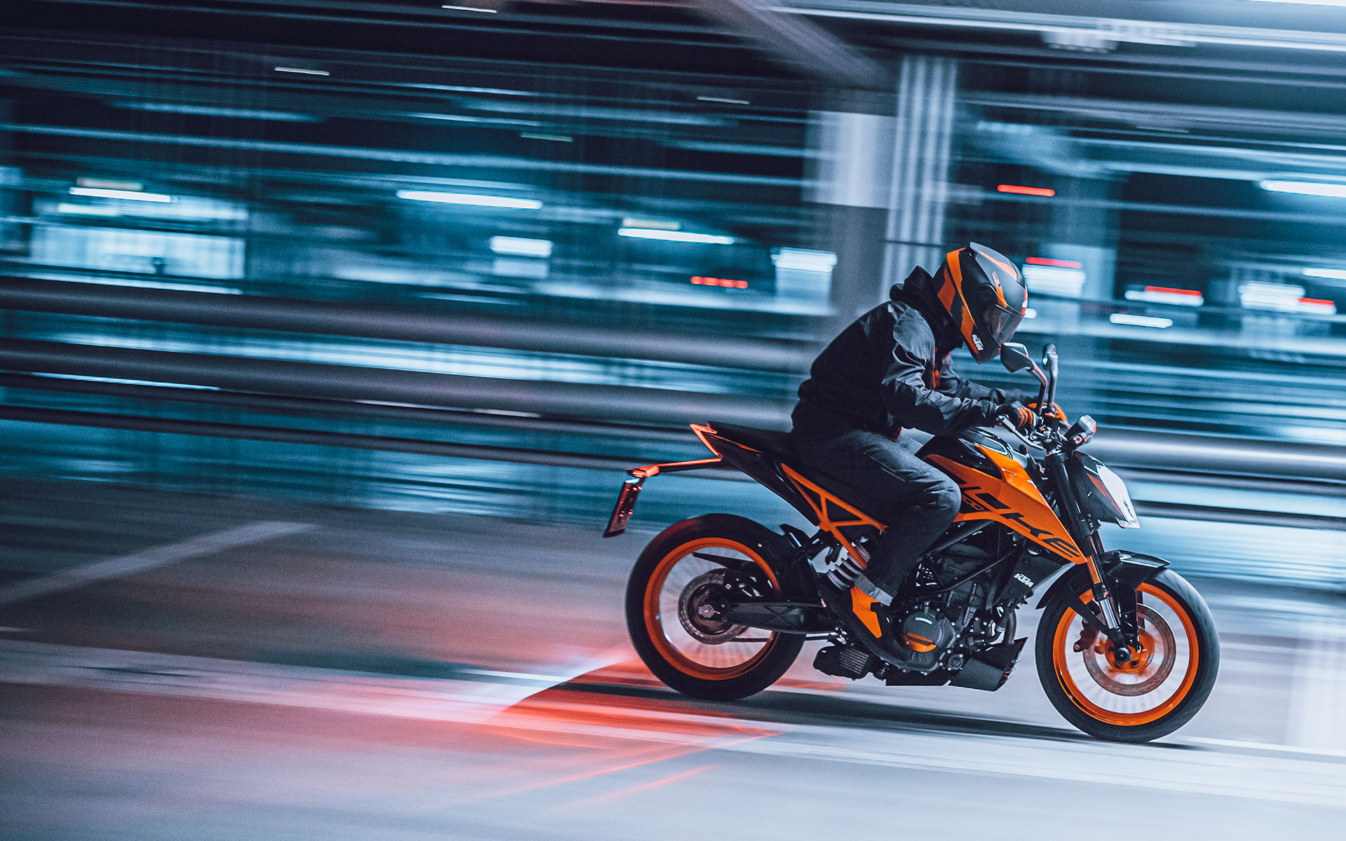 Rider speeding down city street on orange KTM Duke 200