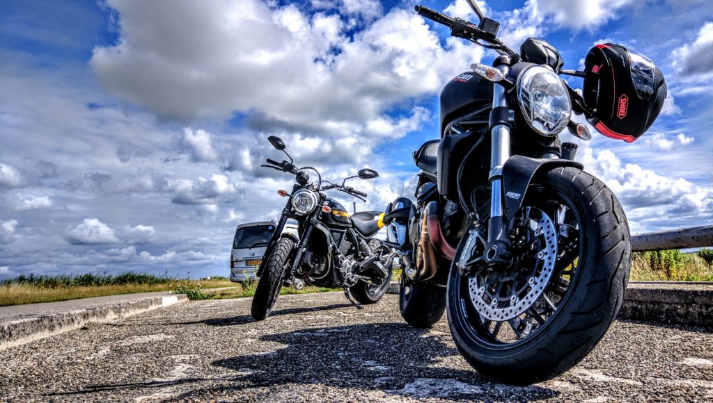 A view of a motorcycle and a few others under clouds and a blue sky