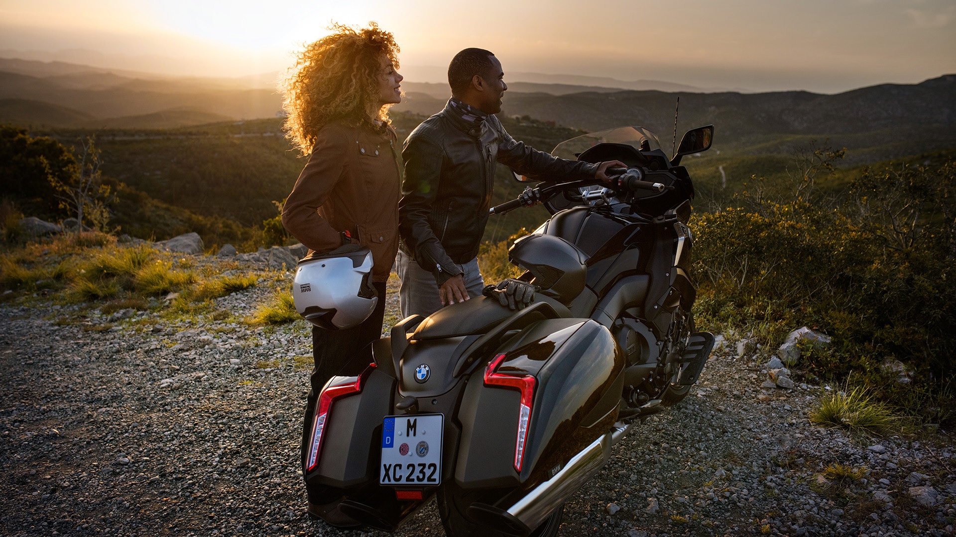 Two riders looking at a sunset next to a 2019 BMW K 1600