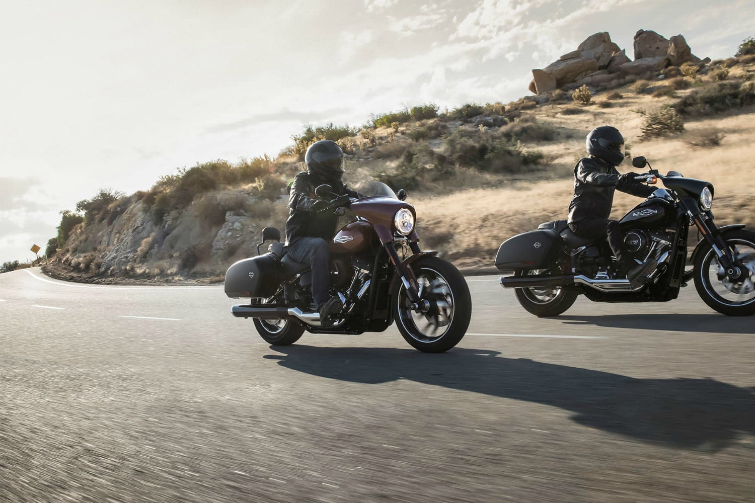 A view of two motorcyclists enjoying a ride on a sunny day with a hilly topography in the background