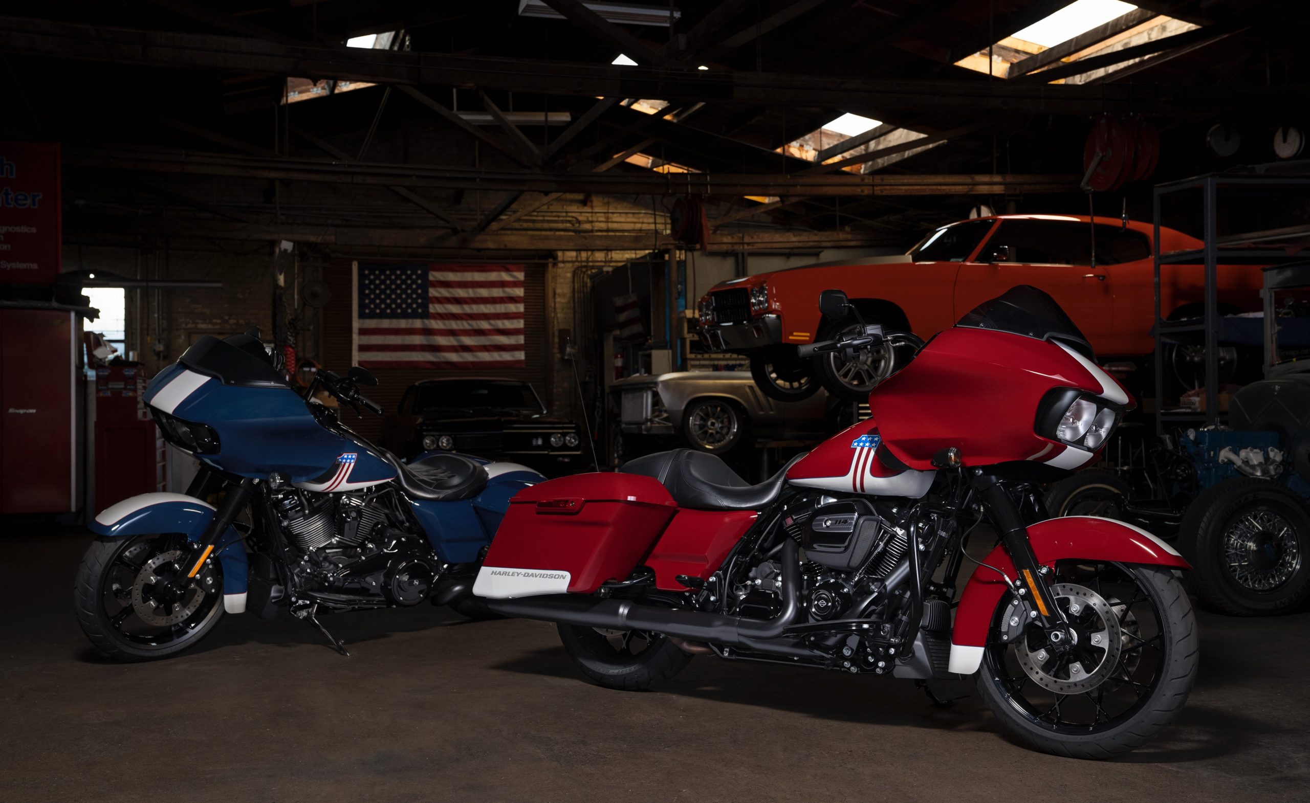 A view of two Harley-Davidson baggers in front of two classic cars