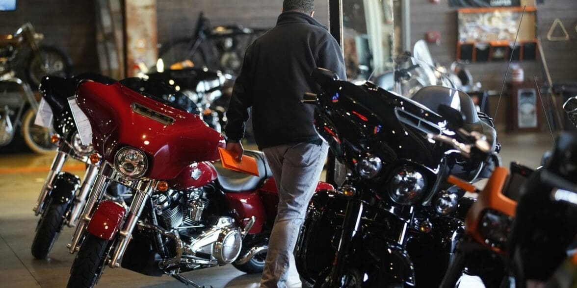 A motorcyclist walking between lines of motorcycles on a dealership floor