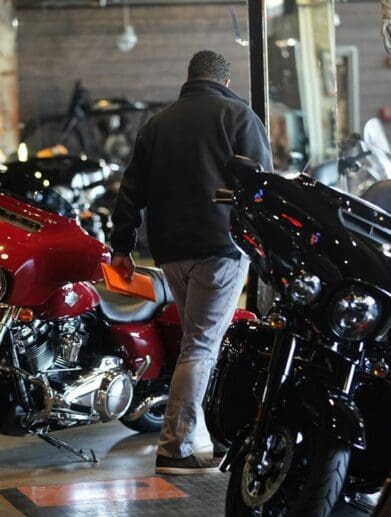 A motorcyclist walking between lines of motorcycles on a dealership floor