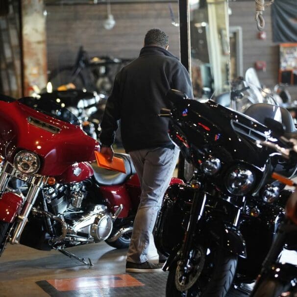 A motorcyclist walking between lines of motorcycles on a dealership floor