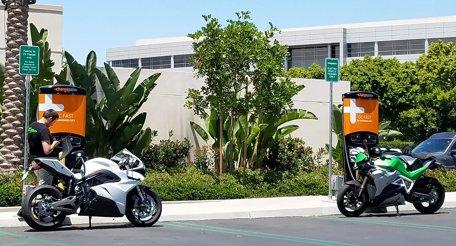 motorcycle riders checking their bikes and charging at a station network