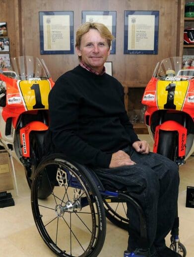 Wayne Rainey in his wheelchair with his championship winning bikes behind him