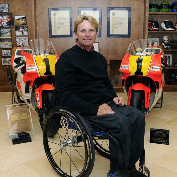 Wayne Rainey in his wheelchair with his championship winning bikes behind him