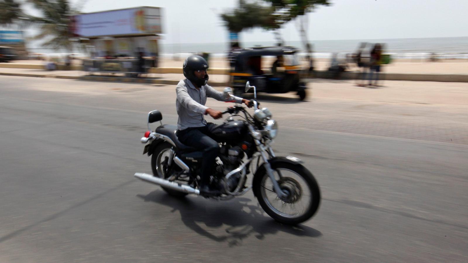 a man riding a Royal Enfield motorcycle near the beach in India