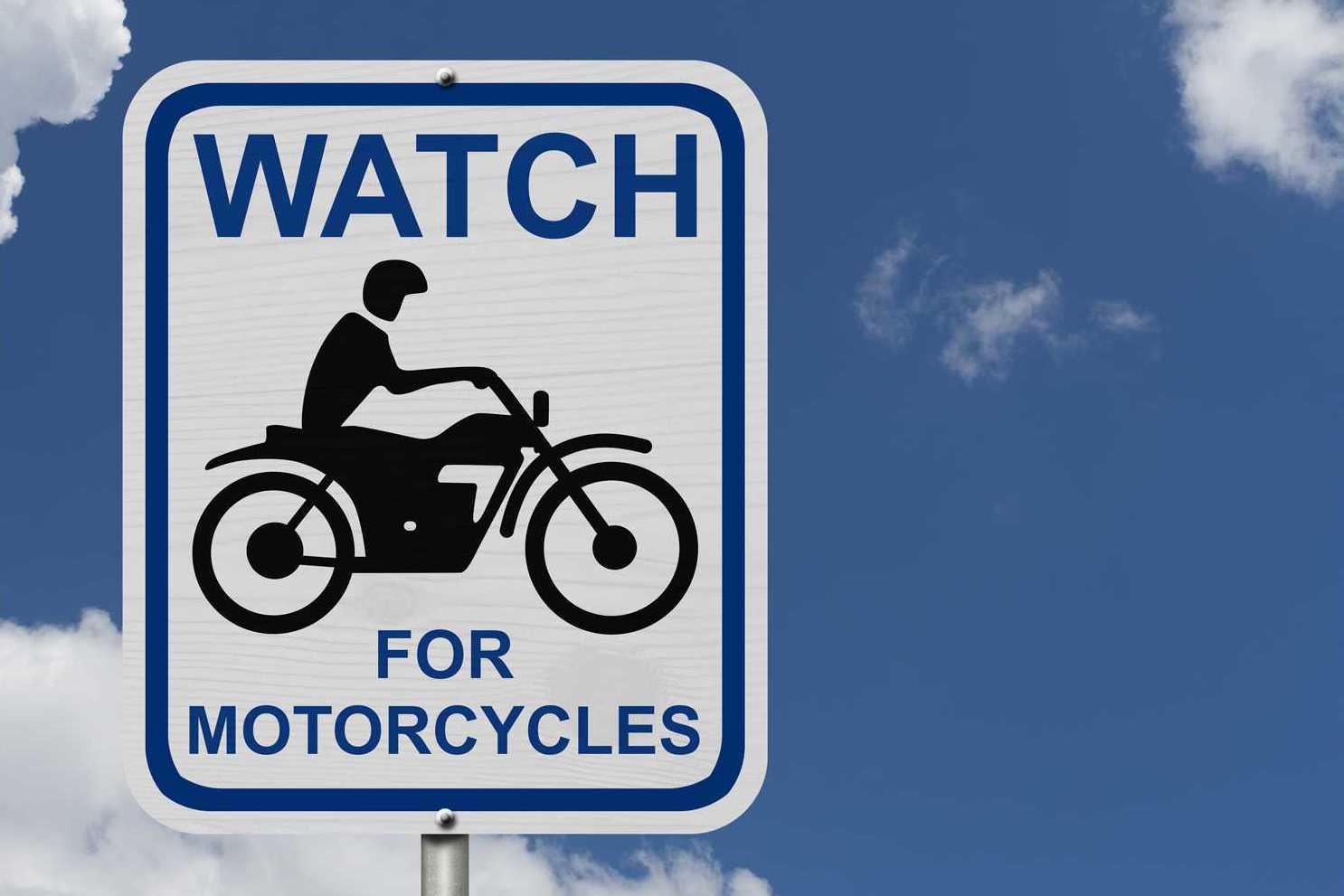 Female student with helmet taking motorcycle lessons and practicing ride. In background traffic cones and instructor with checklist rating and evaluating the ride. Motorcycle school of driving.