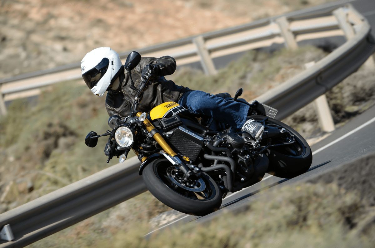 A rider in a white helmet leaning Yamaha's XSR900 into the twisties. 