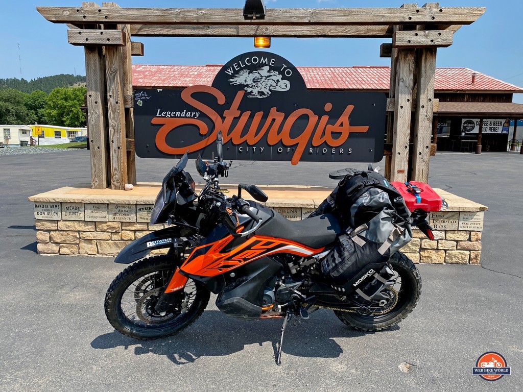 A KTM 790 Adventure parked in front of the Sturgis city sign.