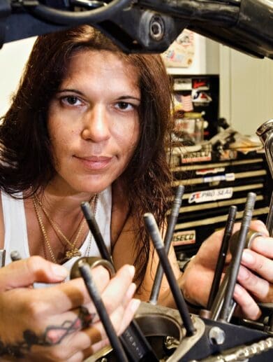 A woman looking through the guts of a motorbike. Photo courtesy of Woman Rider.