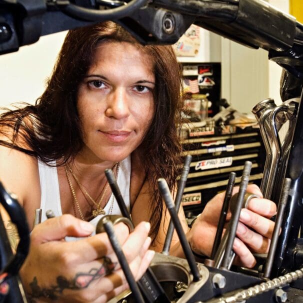 A woman looking through the guts of a motorbike. Photo courtesy of Woman Rider.