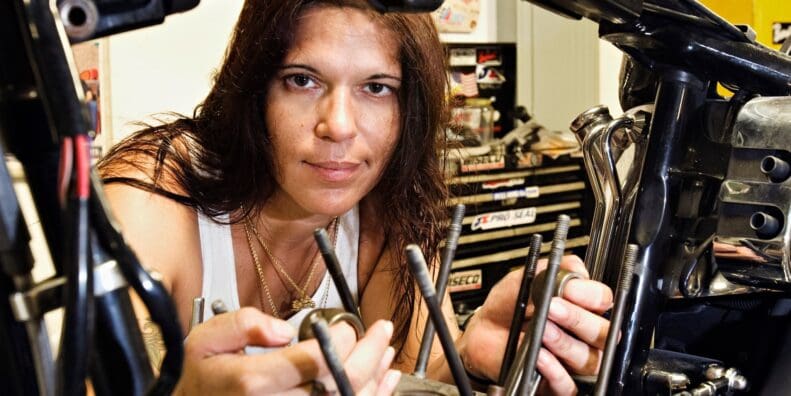 A woman looking through the guts of a motorbike. Photo courtesy of Woman Rider.