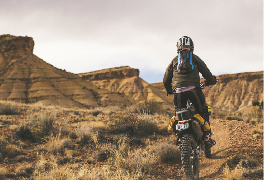 A back view of a motorcyclist riding off-road.