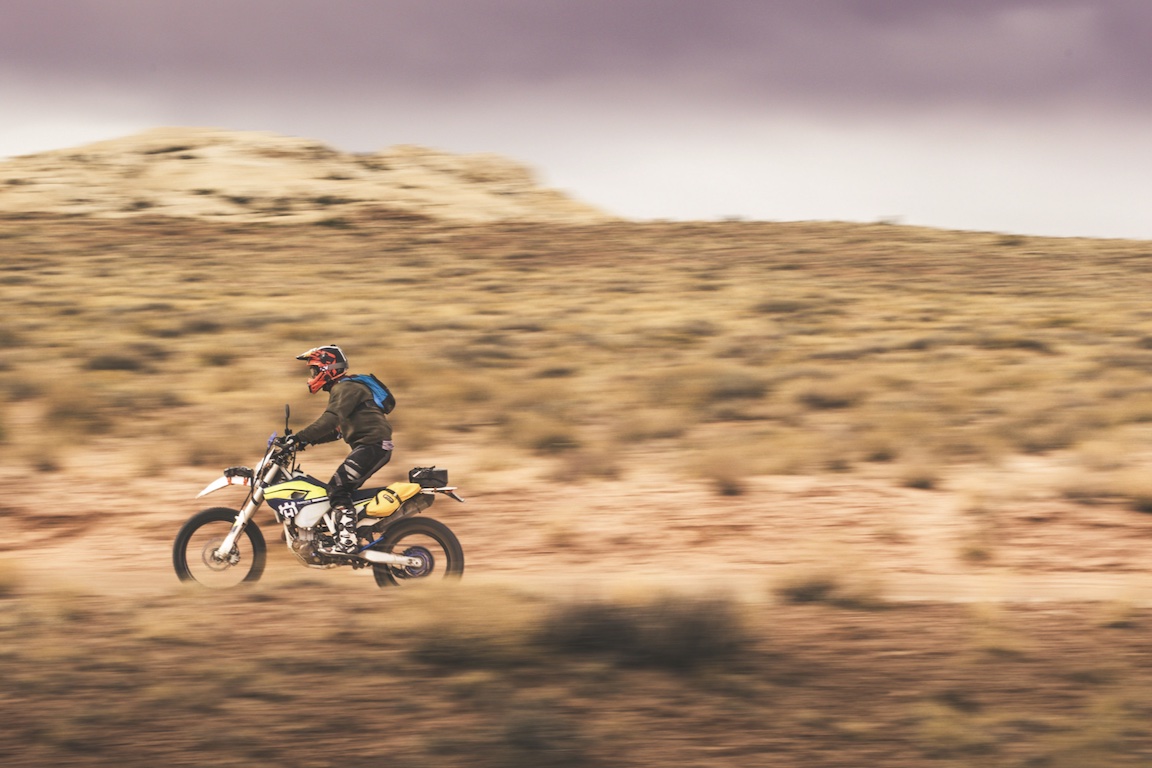 A side view of a motorcyclist riding off-road.