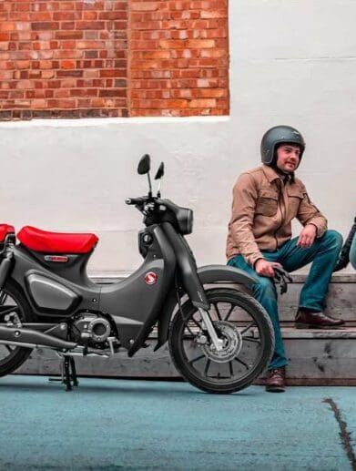 Two riders sitting near Honda Super Cub